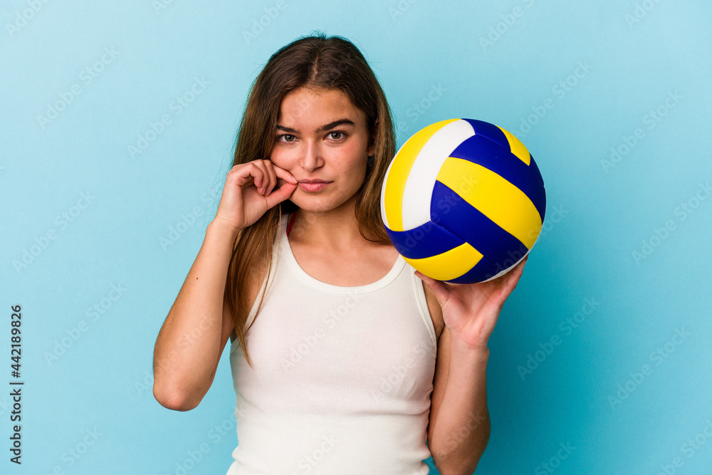 Young caucasian woman playing volleyball isolated on blue background with fingers on lips keeping a secret. Young caucasian woman playing volleyball isolated on blue background with fingers on lips keeping a secret.