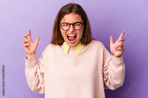 Young caucasian woman isolated on purple background screaming with rage.