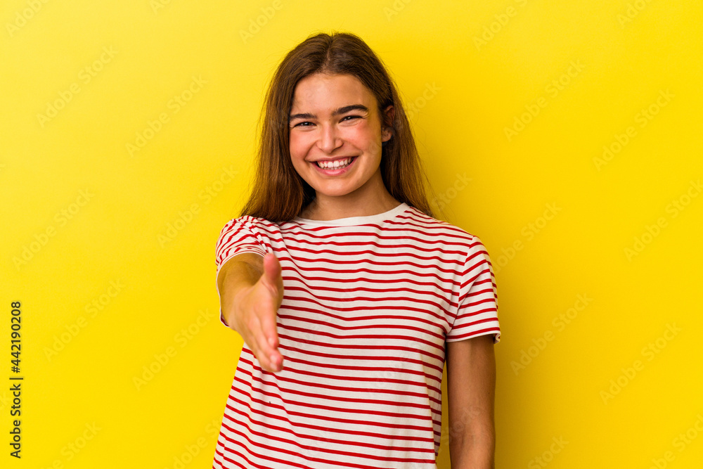 Obraz premium Young caucasian woman isolated on yellow background stretching hand at camera in greeting gesture.