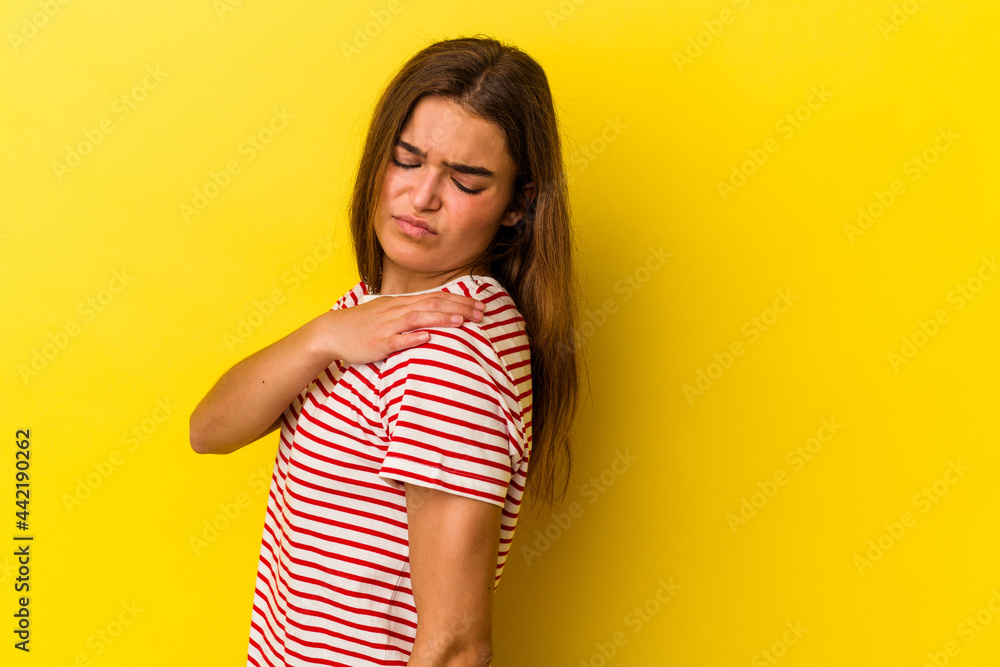 Young caucasian woman isolated on yellow background having a shoulder pain. Young caucasian woman isolated on yellow background having a shoulder pain.