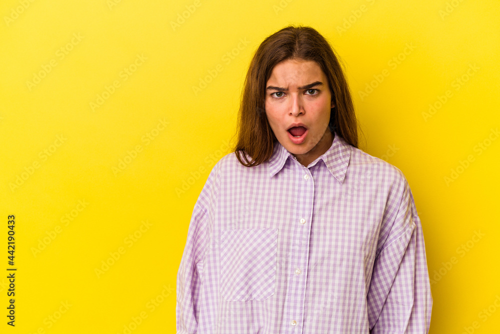 Young caucasian woman isolated on yellow background being shocked because of something she has seen. Young caucasian woman isolated on yellow background being shocked because of something she has seen.