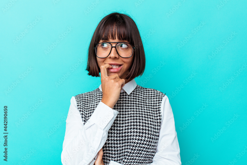 Young mixed race woman isolated on blue background relaxed thinking about something looking at a copy space. Young mixed race woman isolated on blue background relaxed thinking about something looking at a copy space.