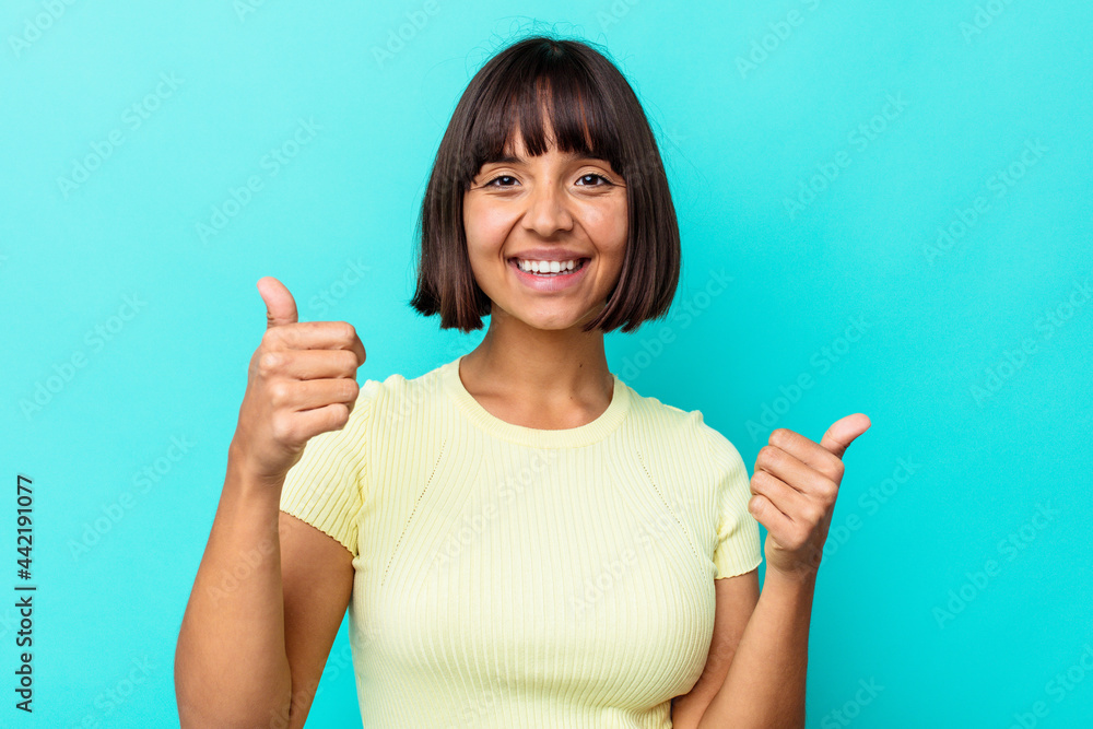 Young mixed race woman isolated on blue background raising both thumbs up, smiling and confident. Young mixed race woman isolated on blue background raising both thumbs up, smiling and confident.