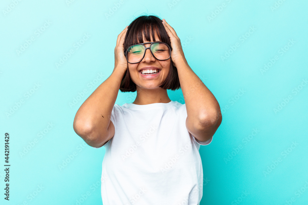 Young mixed race woman isolated on blue background laughs joyfully keeping hands on head. Happiness concept. Young mixed race woman isolated on blue background laughs joyfully keeping hands on head. Happiness concept.