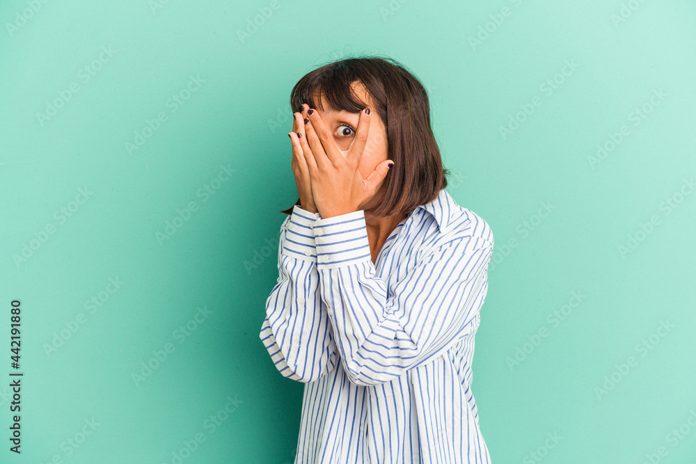 Young mixed race woman isolated on blue blink through fingers frightened and nervous. Young mixed race woman isolated on blue blink through fingers frightened and nervous.