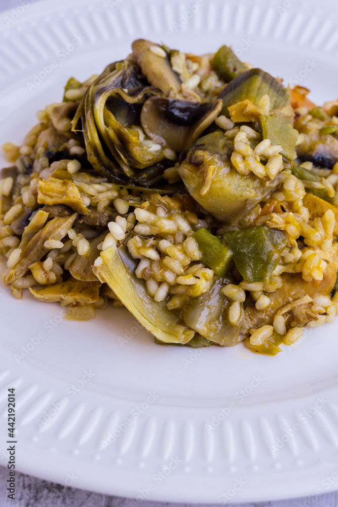 Close up view of rice paella with vegetables on wooden table