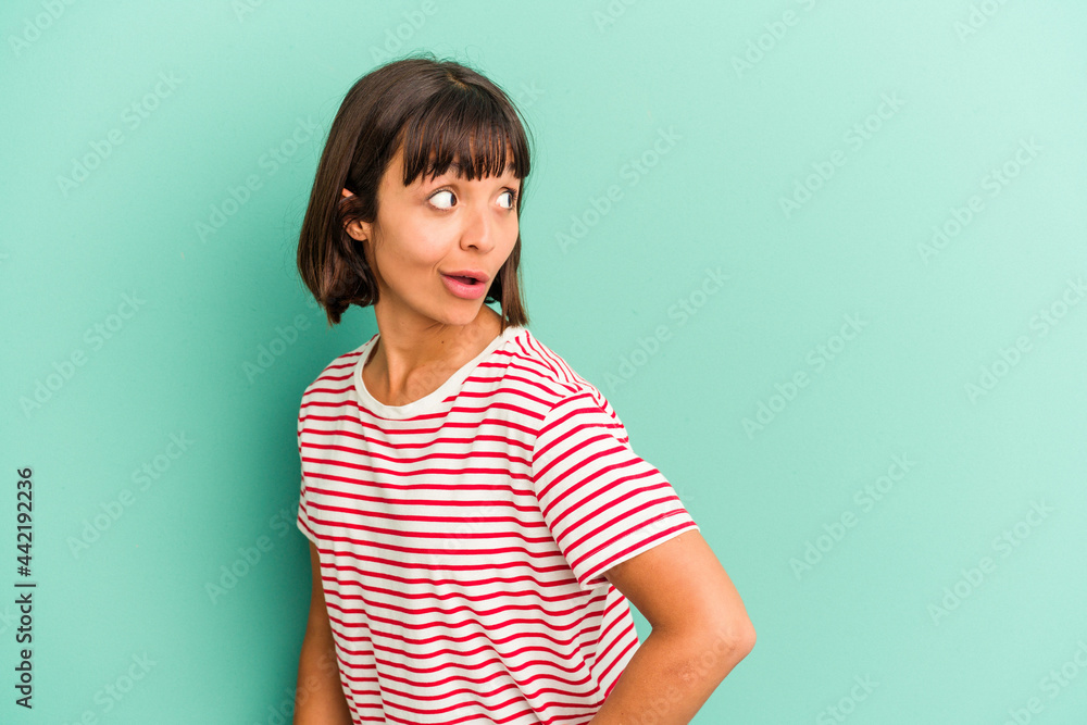 Young mixed race woman isolated on blue looks aside smiling, cheerful and pleasant. Young mixed race woman isolated on blue looks aside smiling, cheerful and pleasant.