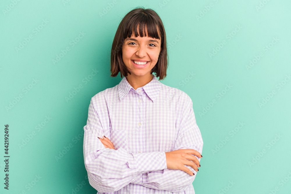 Young mixed race woman isolated on blue who feels confident, crossing arms with determination. Young mixed race woman isolated on blue who feels confident, crossing arms with determination.