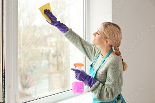 Принти на полотні Young woman washing window in her flat