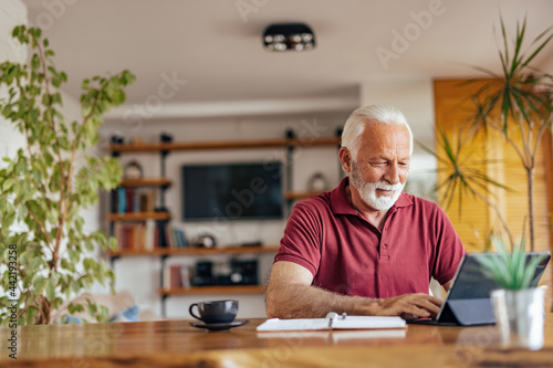 Senior man, working on his book, while drinking his coffee.