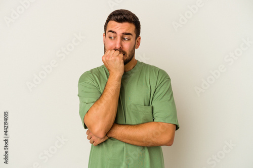 Young caucasian man isolated on white background biting fingernails, nervous and very anxious.