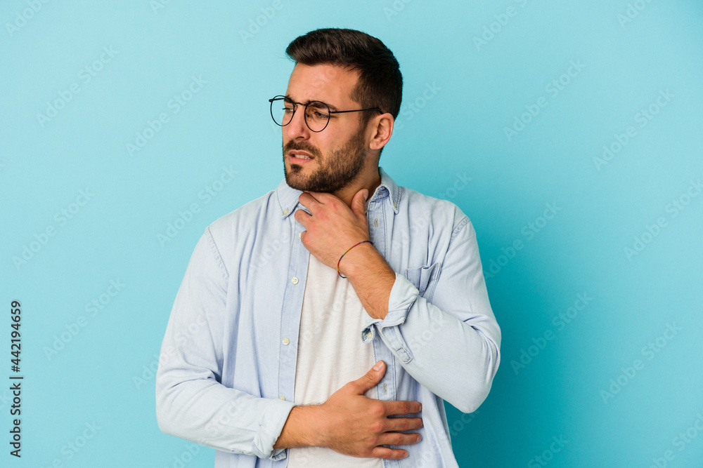 Young caucasian man isolated on blue background suffers pain in throat due a virus or infection. Young caucasian man isolated on blue background suffers pain in throat due a virus or infection.