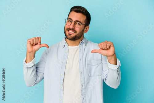 Photography Young caucasian man isolated on blue background feels proud and self confident, example to follow