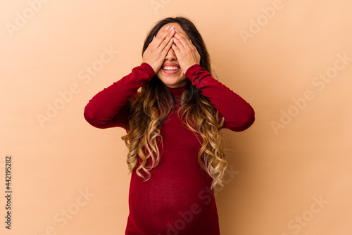 Young mexican pregnant woman isolated on beige background covers eyes with hands, smiles broadly waiting for a surprise.