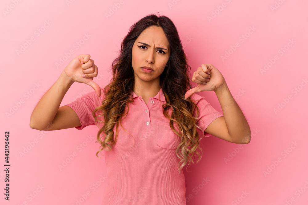 Young mexican woman isolated on pink background showing a dislike gesture, thumbs down. Disagreement concept. Young mexican woman isolated on pink background showing a dislike gesture, thumbs down. Disagreement concept.