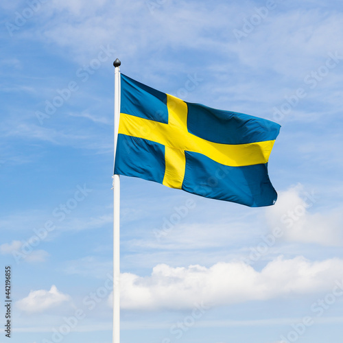 Swedish flag with cloudy sky background.
