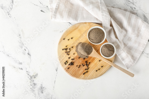 Board with black pepper powder on light background