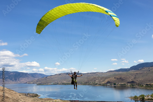 Adventurous Caucasian Woman learning to Fly on a Paraglider around the mountains. Savona, British Columbia, Canada