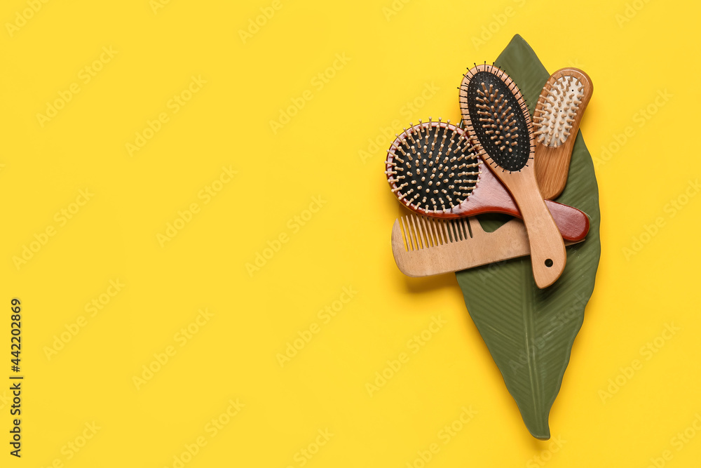 Plate with hair brushes and comb on color background - obrazy, fototapety, plakaty 