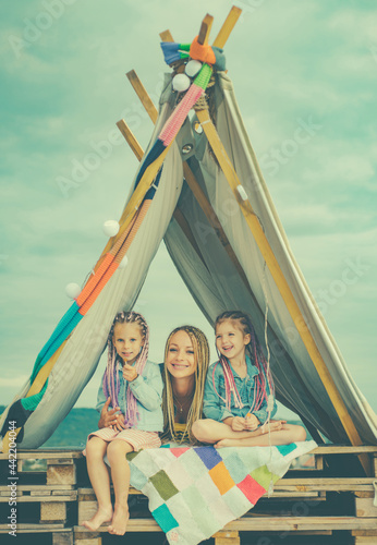 Mom parent with children daughter together. Playing in tent. Family camping. Mom with kids having fun outdoors. Vacation concept. Mothers day. © Volodymyr