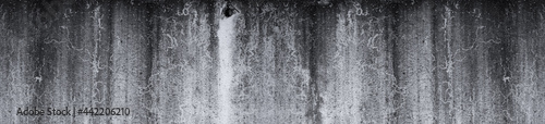 gloomy dark concrete grunge wall with black smudges. Panoramic format for text and design, wide texture background © akintevs