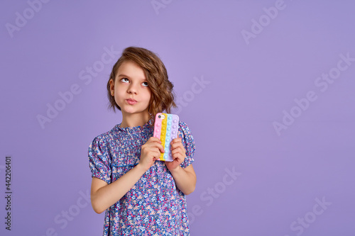 Little girl holding telephone isolated over violet color background © zamuruev