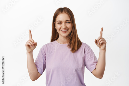 Your logo here. Smiling blond woman pointing fingers up at top advertisement, place for shopping banner, showing announcment or event info, white background photo