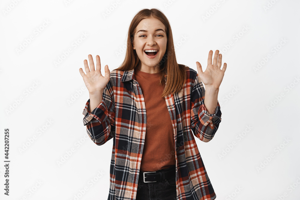 Image of beautiful girl smiling friendly, waving hands to say hello, hi gesture, welcome or greet someone, goodbye wave, standing against white background Image of beautiful girl smiling friendly, waving hands to say hello, hi gesture, welcome or greet someone, goodbye wave, standing against white background