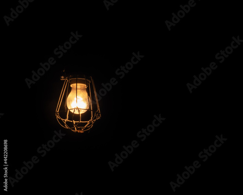 incandescent bulb protected by an iron shell with a totally black background. © rsimona