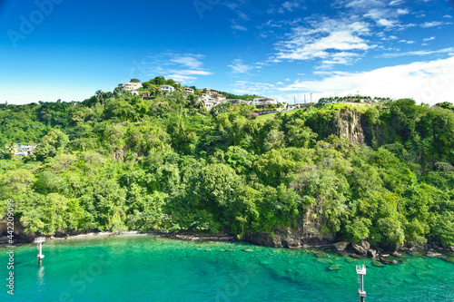 Coastline at Kingstown on Saint Vincent, steep cliff covered by trees behind turquoise and emerald colored water