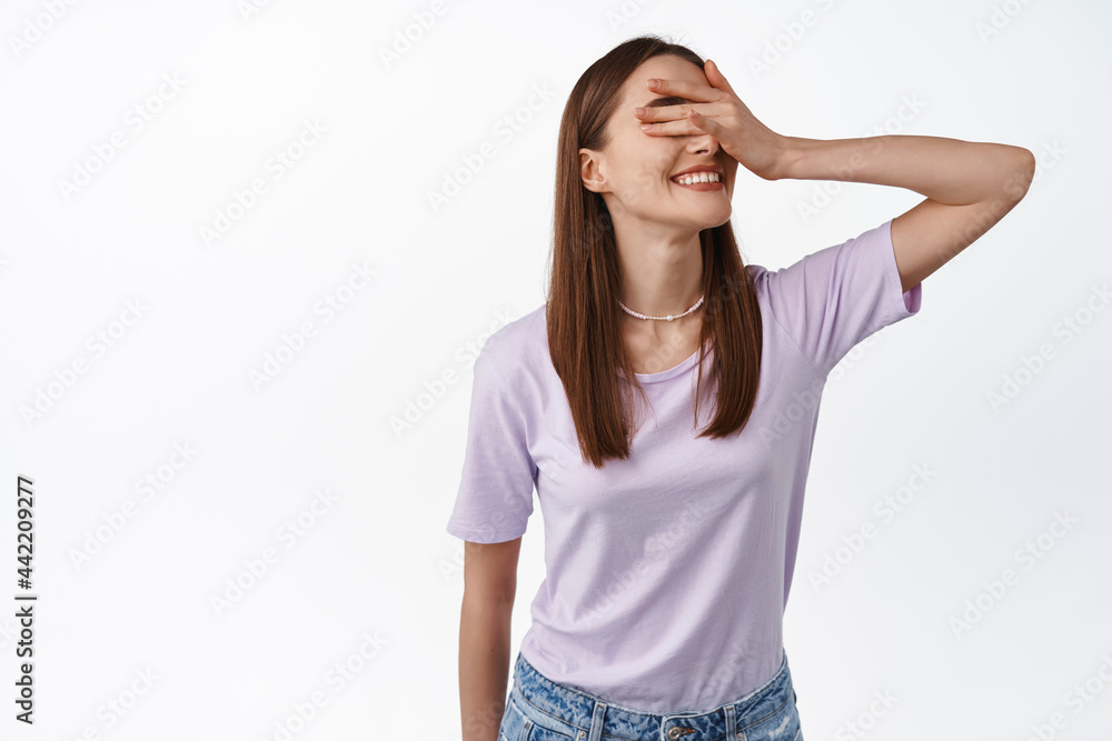 Portrait of beautiful authentic woman close eyes with hand, waiting for surprise, standing blindfolded against white background. Copy space Portrait of beautiful authentic woman close eyes with hand, waiting for surprise, standing blindfolded against white background. Copy space