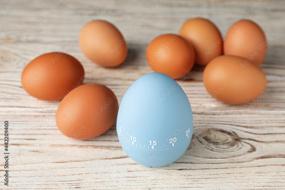 Kitchen timer and eggs on white wooden table Kitchen timer and eggs on white wooden table