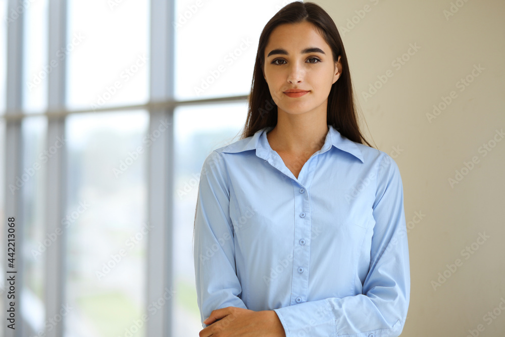A friendly young businesswoman or female student is standing with some papers in the office. Lifestyle and diverse people concept A friendly young businesswoman or female student is standing with some papers in the office. Lifestyle and diverse people concept