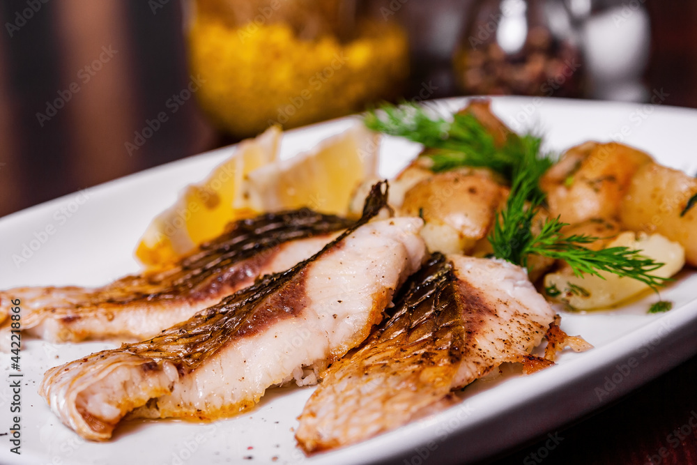 Carp steak with baked potatoes on a white plate Carp steak with baked potatoes on a white plate