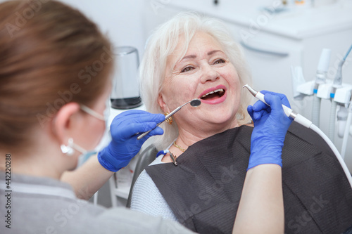 Happy senior woman getting dental treatment by professional dentist