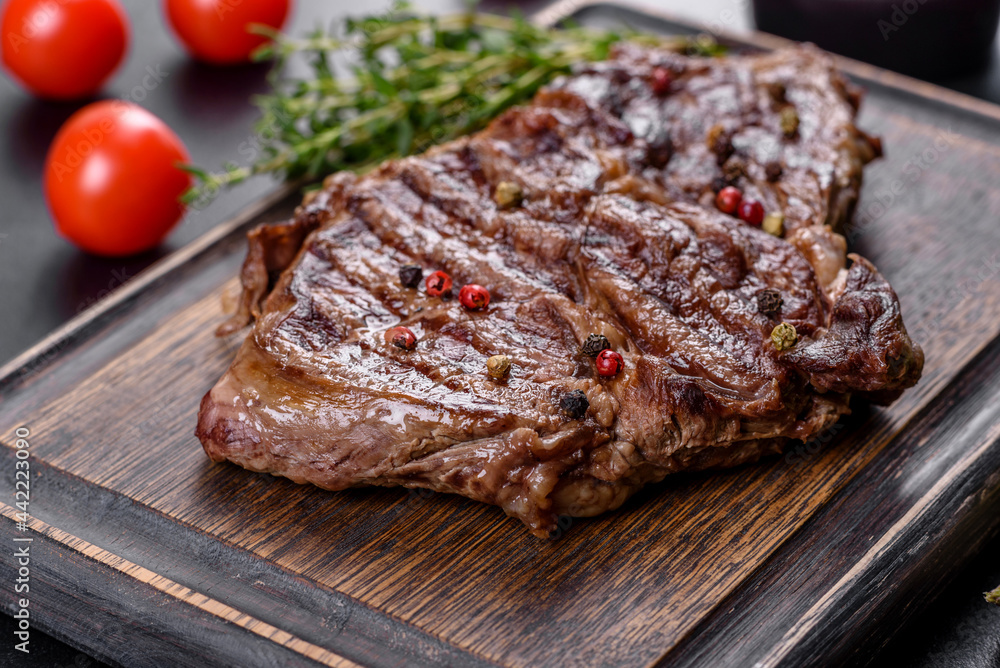 Delicious juicy fresh beef steak with spices and herbs on a dark concrete background Delicious juicy fresh beef steak with spices and herbs on a dark concrete background