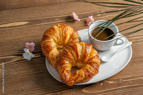French croissants and a cup of coffee on the wooden table. Nice morning breakfast. Food template, top view.