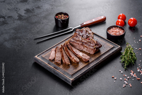 Delicious juicy fresh beef steak with spices and herbs on a dark concrete background