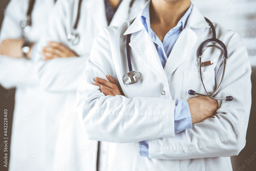 Group of modern doctors standing as a team with arms crossed in hospital office and ready to help patients. Medical help, insurance in health care, best disease treatment and medicine concept Group of modern doctors standing as a team with arms crossed in hospital office and ready to help patients. Medical help, insurance in health care, best disease treatment and medicine concept