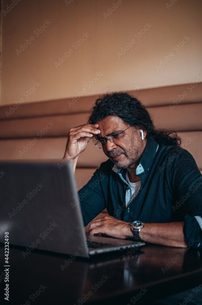 Senior hispanic cuban tired man using a laptop while sitting in a cafe Senior hispanic cuban tired man using a laptop while sitting in a cafe