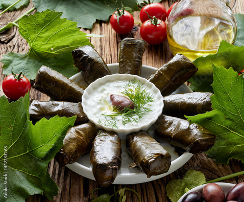Traditional dish, dolmades made of stuffed grape leaves served with yoghurt tzatziki sauce on a wooden table photo
