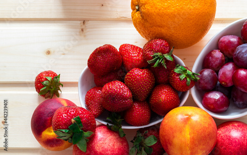 Health and life benefits of strawberries  grapes  nectarines  oranges  high angle photo of fruit on traditional wooden background