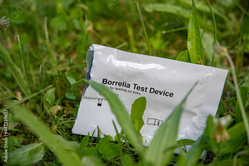 Open Packaging of a Borrelia Test kit in a green meadow. Concept picture for a tick bite photo