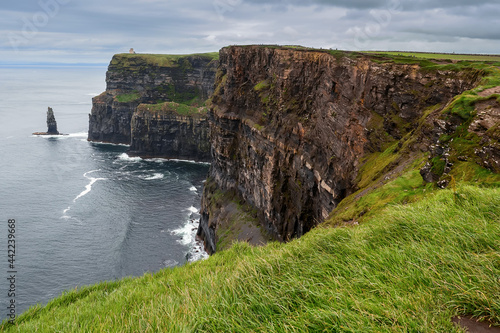 View on Cliff of Moher, county Clare, Ireland. Epic landscape with magnificent scenery. Irish landmark and popular tourist attraction. Atlantic ocean, Cloudy sky