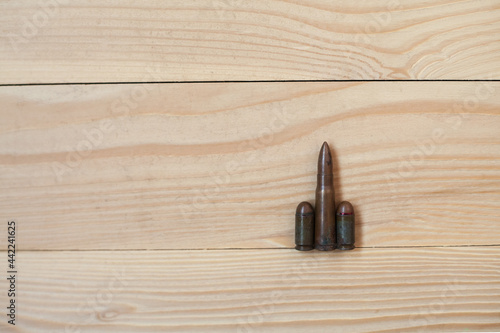 Three different caliber bullets together on a wooden background. Bullets on a wooden background. Military concept.