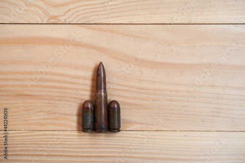 Bullets on a wooden background. Three different caliber bullets together on a wooden background. Military concept.