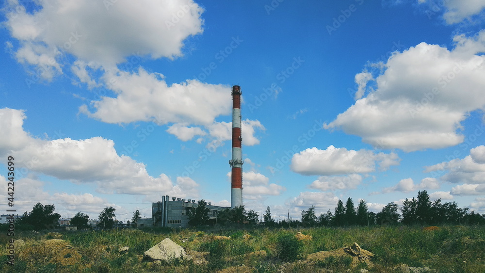 Boiler room chimney against the background of a bright sky and clouds