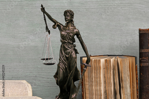 Justitia Figur und alte Bücher auf einem Holzuntergrund. Gerechtigkeit, Waage, Gericht photo