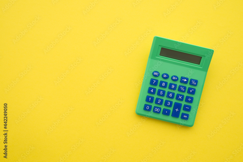 Accounting, tax, banking, business and financial concept. Flat lay or top view of green calculator on yellow table background with blank copy space. Accounting, tax, banking, business and financial concept. Flat lay or top view of green calculator on yellow table background with blank copy space.