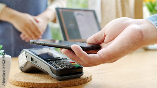 Fotografie Close-up hand asia woman people work in small sme coffee cafe shop store owner use cashless wifi qr code nfc scan app smart pos reader sale in take out food drink order in urban city life contactless